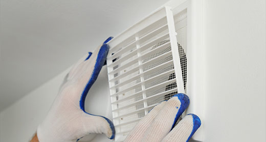 a gloved person installing the grate on a ventilation system